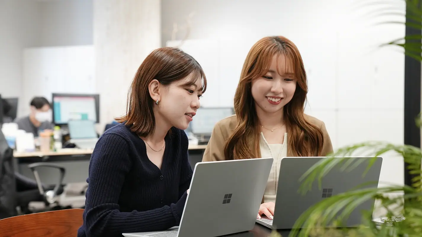 オフィスで並んでパソコンを見ながら会話する社員
